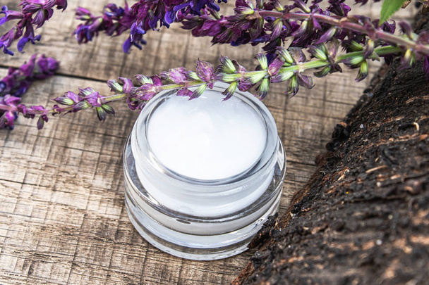 Natural face cream with blue lavender wildflowers on a wooden background. Face cream. - Photo, Image