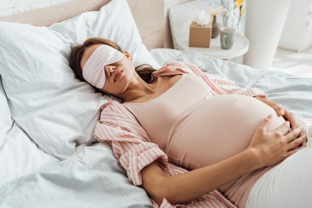 Schwangere liegt in Schlafmaske im Bett - Foto, Bild
