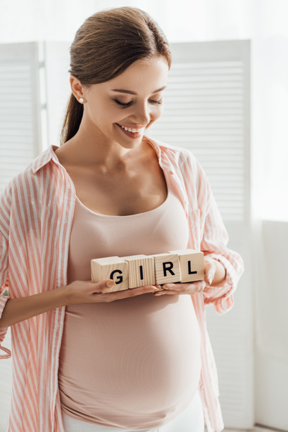 smiling pregnant woman holding wooden blocks with word - Foto, immagini