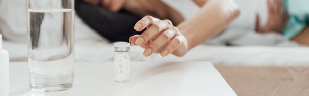panoramische foto van de vrouw met pillen en glas water - Foto, afbeelding