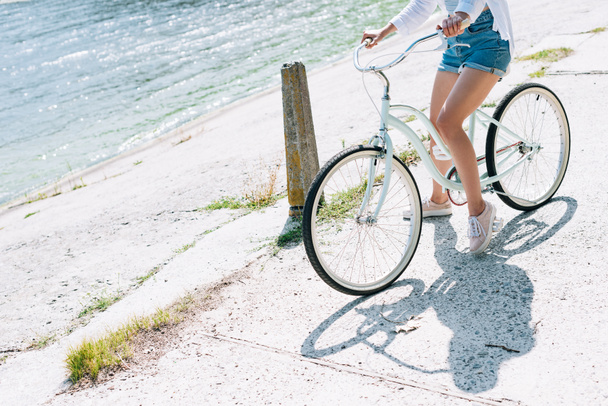 partial view of girl riding bike near river in summer - 写真・画像