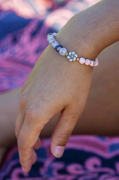 bracelet en perles de pierre minérale avec perle fleur en métal sur la main féminine
 - Photo, image