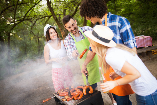 Friends having a barbecue party in nature while having fun - Foto, imagen