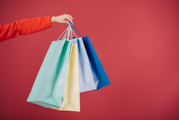 cropped view of woman holding shopping bags isolated on red  - Foto, Imagem