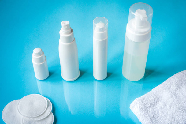 White bottles with skin lotion on a blue background - Foto, afbeelding