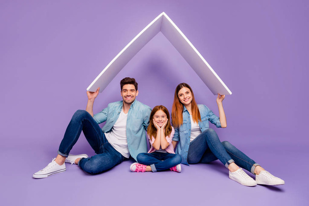 Family portrait of three members sitting floor under new roof wear casual clothes isolated purple background - Foto, Imagem