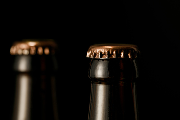 vista ravvicinata di bottiglie di birra in vetro con tappi metallici isolati su nero
 - Foto, immagini