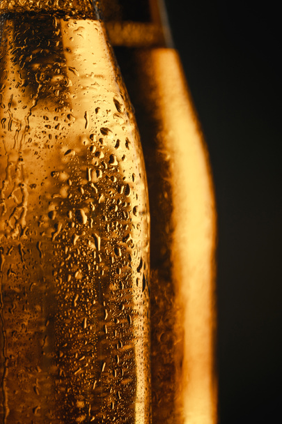 close up view of wet glass bottles of beer isolated on black - Fotografie, Obrázek
