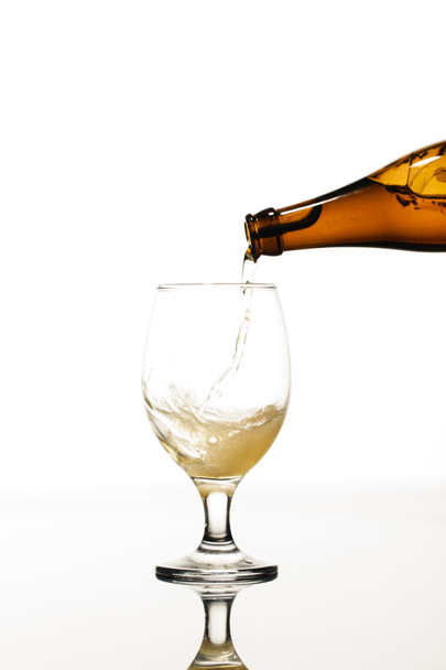 Bière versant de la bouteille dans le verre isolé sur blanc - Photo, image