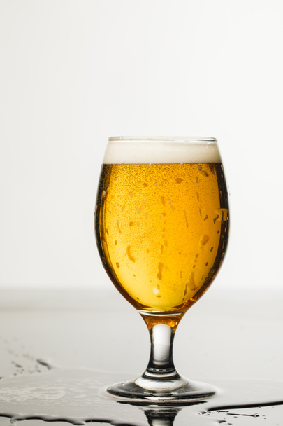 vaso mojado de cerveza con espuma y charco aislado en blanco
 - Foto, Imagen