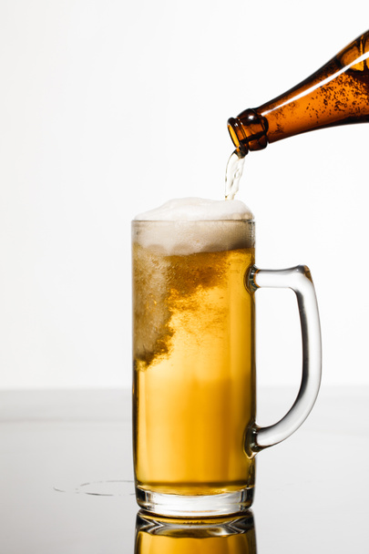 ボトルからガラスに注ぐビールは、白で分離された泡で - 写真・画像