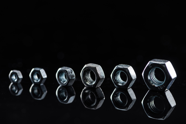 porcas de metal de tamanhos diferentes isoladas em preto
 - Foto, Imagem