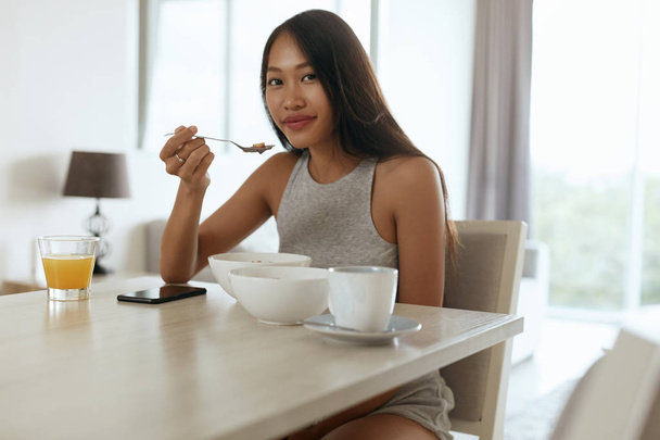 Woman eating healthy breakfast at home in morning at table - Foto, afbeelding