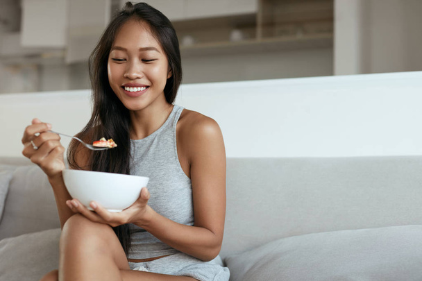 Smiling woman eating healthy breakfast at home in morning - Foto, Imagem