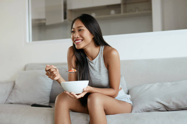 Χαμογελαστή γυναίκα τρώγοντας υγιεινό πρωινό στο σπίτι το πρωί - Φωτογραφία, εικόνα