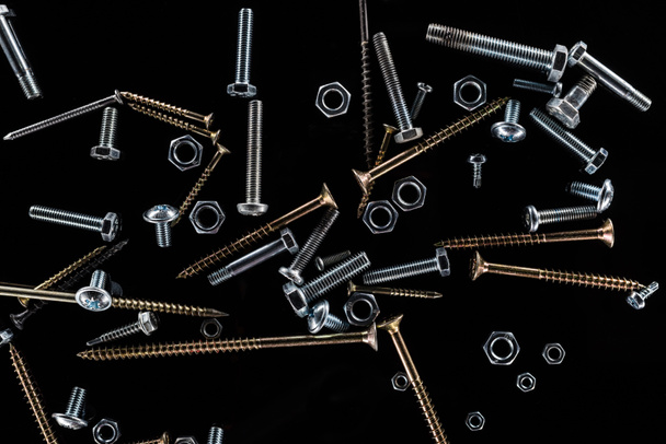 top view of scattered bolts, nuts and studs isolated on black - Photo, Image
