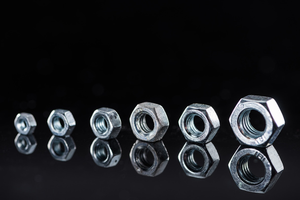 row of brand new shiny metallic nuts isolated on black - Photo, Image