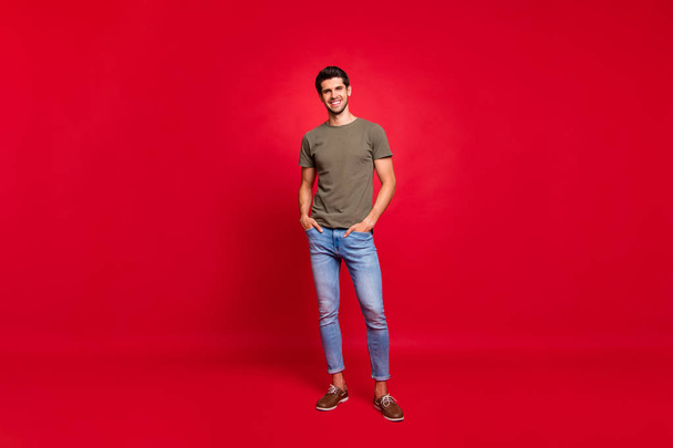 Full length photo of macho guy hold hands pockets street look wear casual outfit isolated on red background - Photo, Image