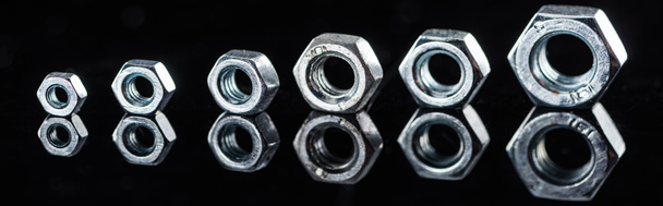 panoramic shot of shiny new metallic nuts isolated on black - Fotografie, Obrázek