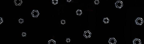 panoramic shot of scattered metal nuts pattern isolated on black - Photo, Image