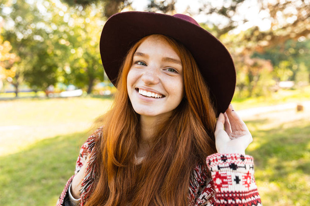 Cheerful smiling happy young student redhead girl in autumn park walking. - Фото, зображення