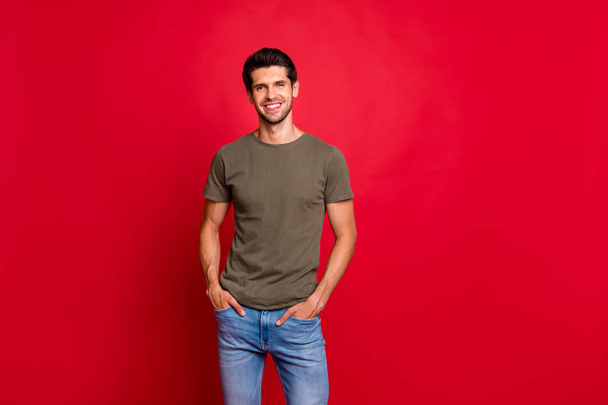 Photo of amazing guy hold hands pockets wear casual grey t-shirt isolated on red background - Фото, изображение
