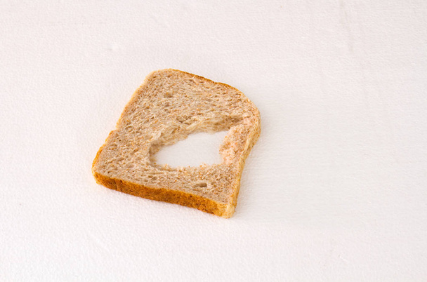 A slice of bread with a chunk missing in the middle isolated on a white background image with copy space - Foto, Bild
