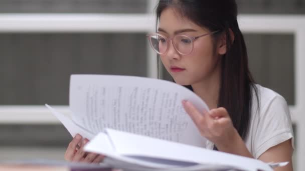 Asijské studentky čtou knihy v knihovně na univerzitě. Mladá vysokoškolská dívka dělá domácí úkoly, čte učebnicovou knížku, pilně studuje vědomosti a vzdělání na přednášce ve školní koleji. Zpomaleně. - Záběry, video