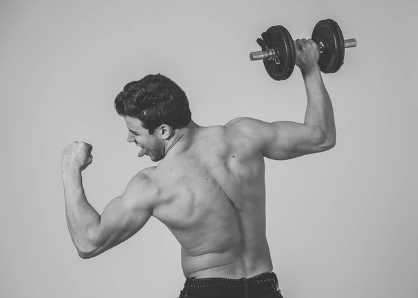 Portrait of young muscular built athlete man working out doing exercises and posing with dumbbells, bodybuilder male naked torso lifting weights in Fitness sports Body care and healthy lifestyle. - Φωτογραφία, εικόνα