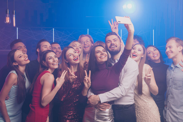 Portrait of nice well-dressed chic glamorous attractive fashionable stylish gorgeous cheerful positive glad ladies and guys having fun taking selfie showing v-sign symbol at luxury fogged nightclub - Fotó, kép