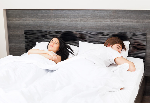 Unhappy separate couple lying in a bed - Фото, изображение