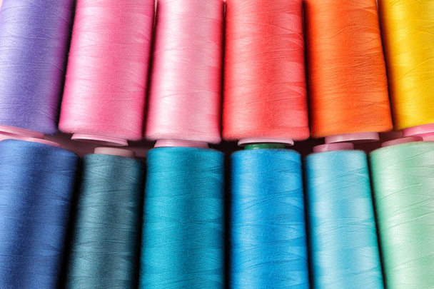 Аксессуары для шитья и рукоделия. Много разноцветных катушек трехцветных. Бобины с цветной нитью
 - Фото, изображение