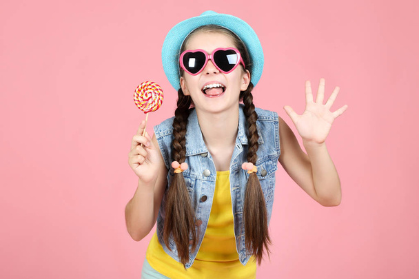 Beautiful young girl with sweet lollipop on pink background - 写真・画像