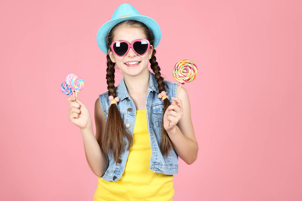 Beautiful young girl with sweet lollipops on pink background - Foto, imagen