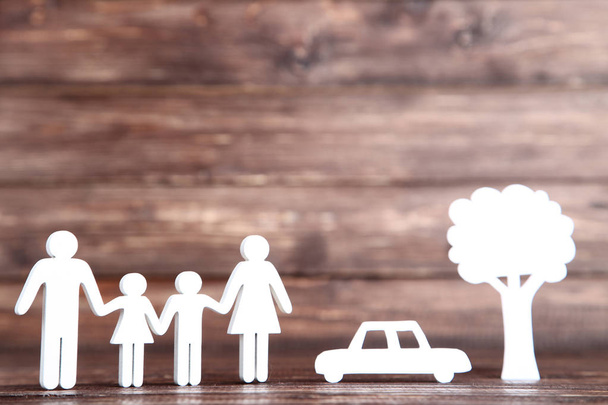 Wooden family figures with paper car and tree on brown backgroun - Фото, изображение