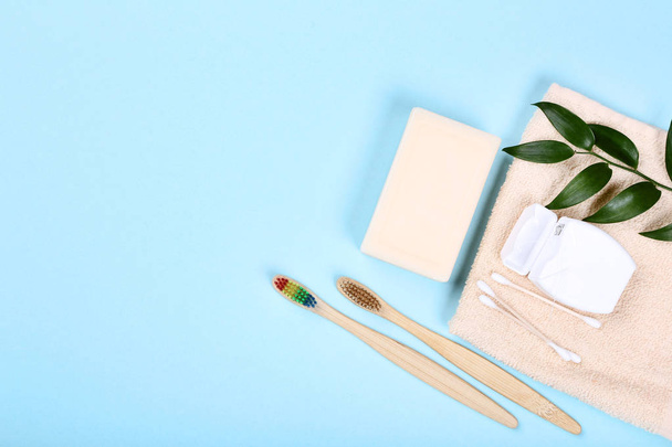 Бамбуковые зубные щетки с мылом, хлопковыми палочками и зубной нитью на синем фоне
 - Фото, изображение
