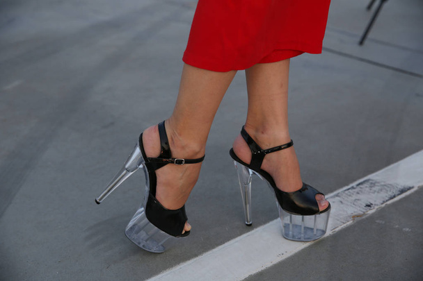 jambes féminines en pantalon large rouge et des sandales avec des talons très hauts se tiennent sur la ligne blanche des pieds. Beauté et mode des femmes
. - Photo, image