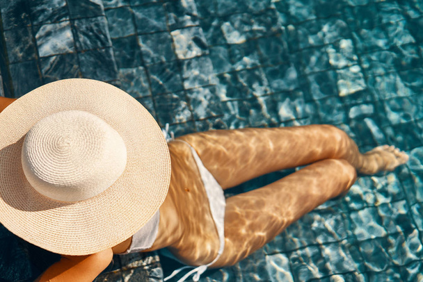 γυναίκα σε μεγάλο καπέλο με λεπτό σώμα χαλαρωτικό στην πισίνα - Φωτογραφία, εικόνα