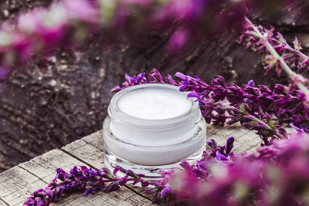 Cosmetic cream and fresh lavender wildflowers on a wooden background. Face cream. - Photo, Image
