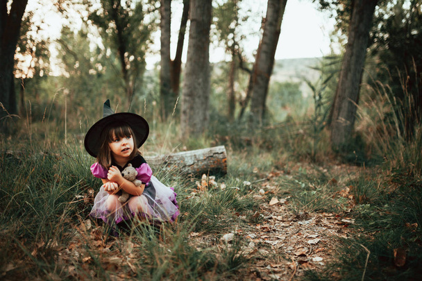 Lächelndes Mädchen verkleidet als Hexe im Wald zu Halloween - Foto, Bild