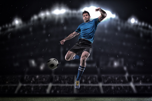 Voetballer in actie op een donkere achtergrond - Foto, afbeelding