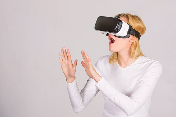 Woman wearing virtual reality goggles. Person with virtual reality helmet isolated on grey background. Woman with virtual reality headset. VR gaming. - Foto, afbeelding