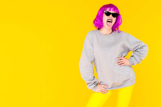 Retrato de chica de moda sobre fondo amarillo. Mujer joven de estilo loco en peluca rosa
 - Foto, imagen