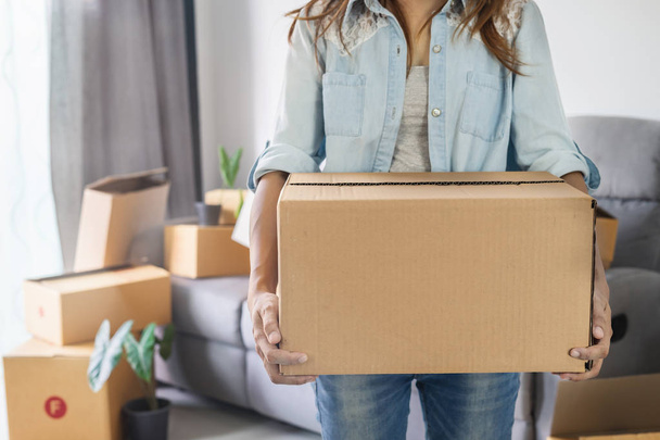 Joven mujer feliz moviéndose en un nuevo hogar y llevando una caja de cartón
 - Foto, imagen
