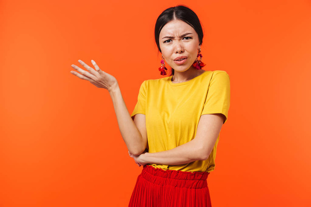 Confused displeased young woman posing isolated over orange wall background. - Foto, Imagem