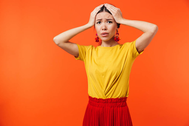 Confused displeased young woman posing isolated over orange wall background. - Photo, image