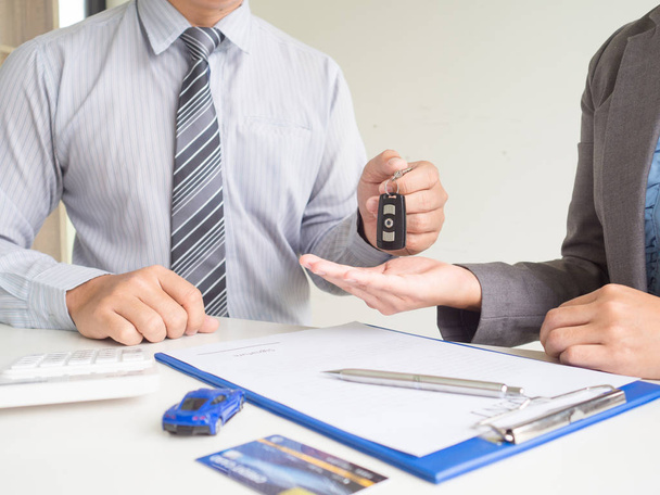 Продавец дает ключ клиенту Деловая женщина после подписания договора аренды автомобиля
 - Фото, изображение