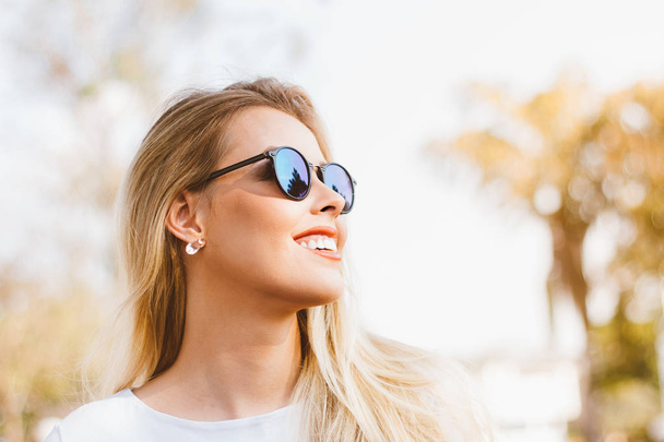 Outdoor fashion portrait of young smiling modern latin woman - Brazilian with retro sunglasses - Happy with the arrival of summer. Hot yellow filter. Fashion, trendy and millennial generation concept - Photo, Image