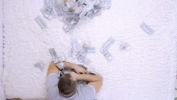 Vrouwelijke en mannelijke gooien op elkaar een heleboel bankbiljetten van dollars op het bed, Slow Motion, Top uitzicht - Video