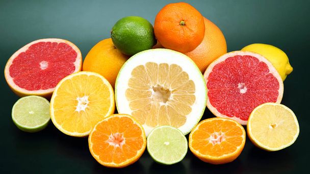 Koyu arkaplanda farklı turunçgil meyveleri kes - Fotoğraf, Görsel